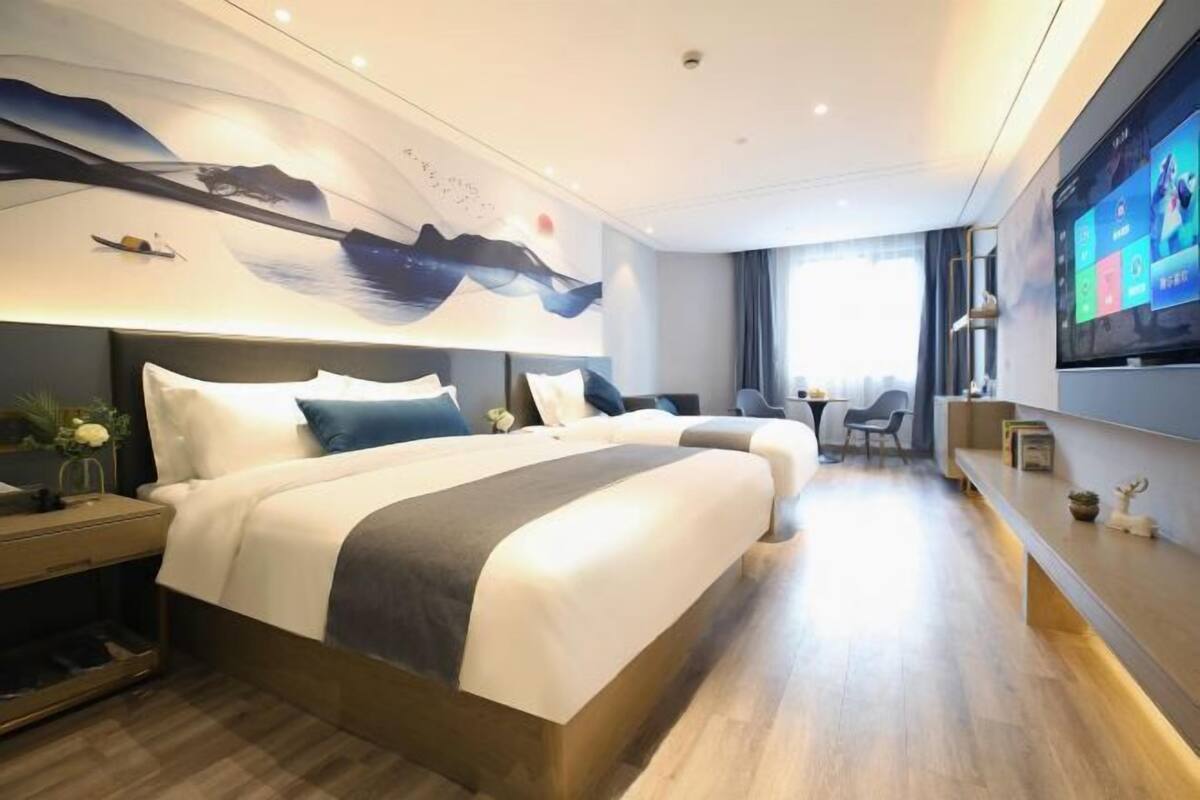 Una habitación de hotel moderna con una cama grande, un escritorio, un televisor y un mural en la pared.