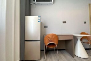 A compact kitchenette with a refrigerator, a small table, and two chairs.
