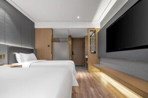 Et moderne hotelværelse med en stor seng, et fladskærms-TV monteret på væggen og en træpanelfront.