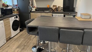 A modern kitchen with a central island, built-in appliances, and a dining area with bar stools.