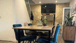 A dining area with a wooden table, blue upholstered chairs, and a stone accent wall.
