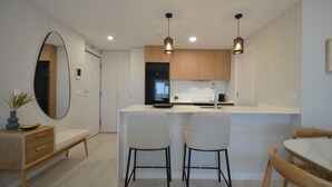 A modern kitchen with a central island, two bar stools, and pendant lighting.