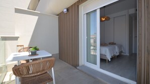 A balcony with a table, chairs, and a potted plant.