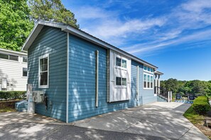 Une maison de plain-pied à l’extérieur bleu, dotée d’un porche et d’un coffret électrique visible.