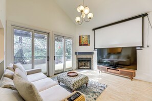 A living room with a sofa, ottoman, fireplace, and a large TV screen.