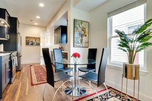 A modern kitchen with dark cabinets, a glass-top dining table, and a red vase with flowers. - Walk to Parks: Dog-Friendly Gem in Indianapolis! (Indianapolis)