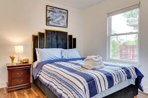 A bedroom with a bed, a nightstand, a lamp, and a window with a view of the outside. - Walk to Parks: Dog-Friendly Gem in Indianapolis! (Indianapolis)