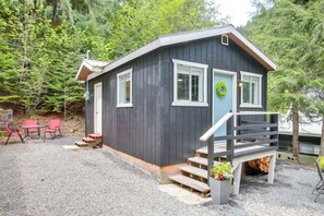 Escape to a serene forest setting, surrounded by nature, with a cozy cabin featuring a welcoming front door and a small porch.