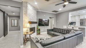 Un salon moderne avec un canapé d’angle, une cheminée et un téléviseur à écran plat.