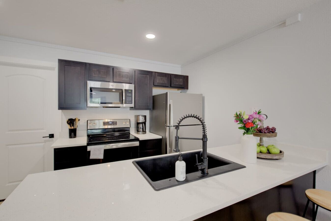 A modern kitchen with a central island, stainless steel appliances, and a decorative vase with flowers.