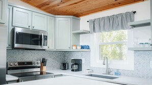 A modern kitchen with white cabinets, a stainless steel microwave, an oven, and a coffee maker. - Pops Cozy Cabin w/ an incredible valley view. Gas firepit, full kitchen and more (Fancy Gap)