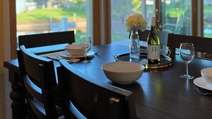 A dining area with a dark wooden table, chairs, and a geometric pendant light fixture. - Charming 3-bedroom riverside cottage in brilliant Tawas City (Tawas City)