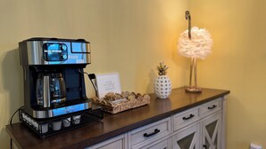 A coffee maker on a wooden counter with a sign, a pineapple-shaped vase, and a lamp. - Charming 3-bedroom riverside cottage in brilliant Tawas City (Tawas City)