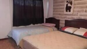 Une chambre avec deux lits, un mur en bois et un tableau encadré.