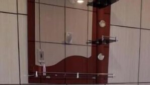 Une salle de bain avec un lavabo blanc, un miroir avec un cadre en bois et une poubelle rouge.
