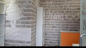 Un área de recepción con una pared de ladrillo, un mostrador de recepción blanco y un letrero que dice "HOSTAL NORTH".