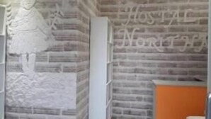 Un mur de briques avec une vue partielle d’une porte blanche et d’une étagère.