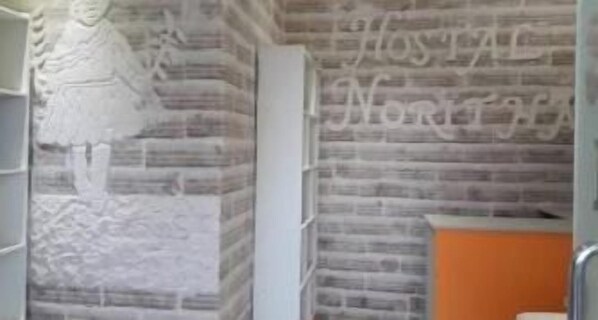 A brick wall with a partial view of a white door and a shelf unit. - Hostal de Sal Noritha (Uyuni)