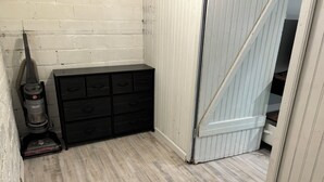A room with a black storage unit, a vacuum cleaner, and a partially open door leading to another room. - Studio-close to Cleveland clinic With WiFi and AC in Cleveland Heights (Cleveland Heights)