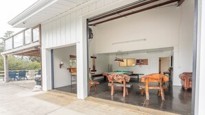 A covered outdoor area with a pool table, pool cues, and chairs. - Family Night's Rest | Game Room | Fort Bragg (Fort Bragg)
