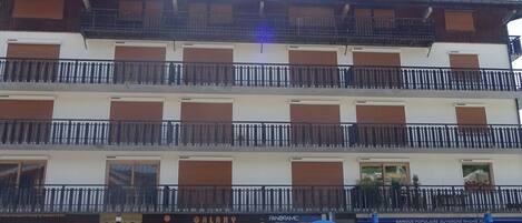 Un edificio de varios pisos con balcones y un escaparate con el nombre