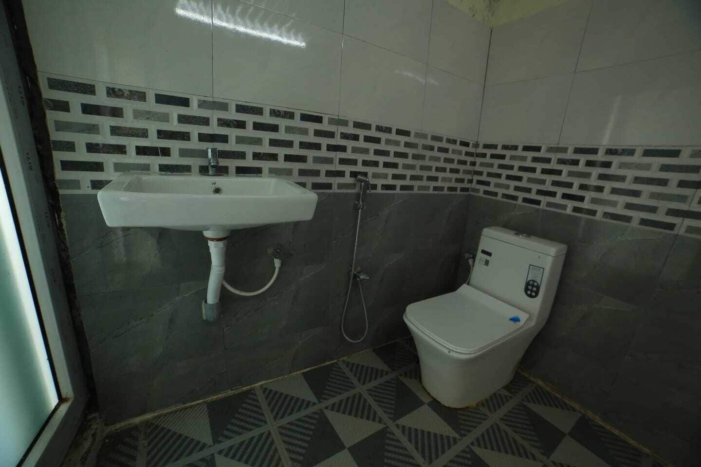 A bathroom with a white sink, a toilet, and a shower. The walls have a brick pattern design.