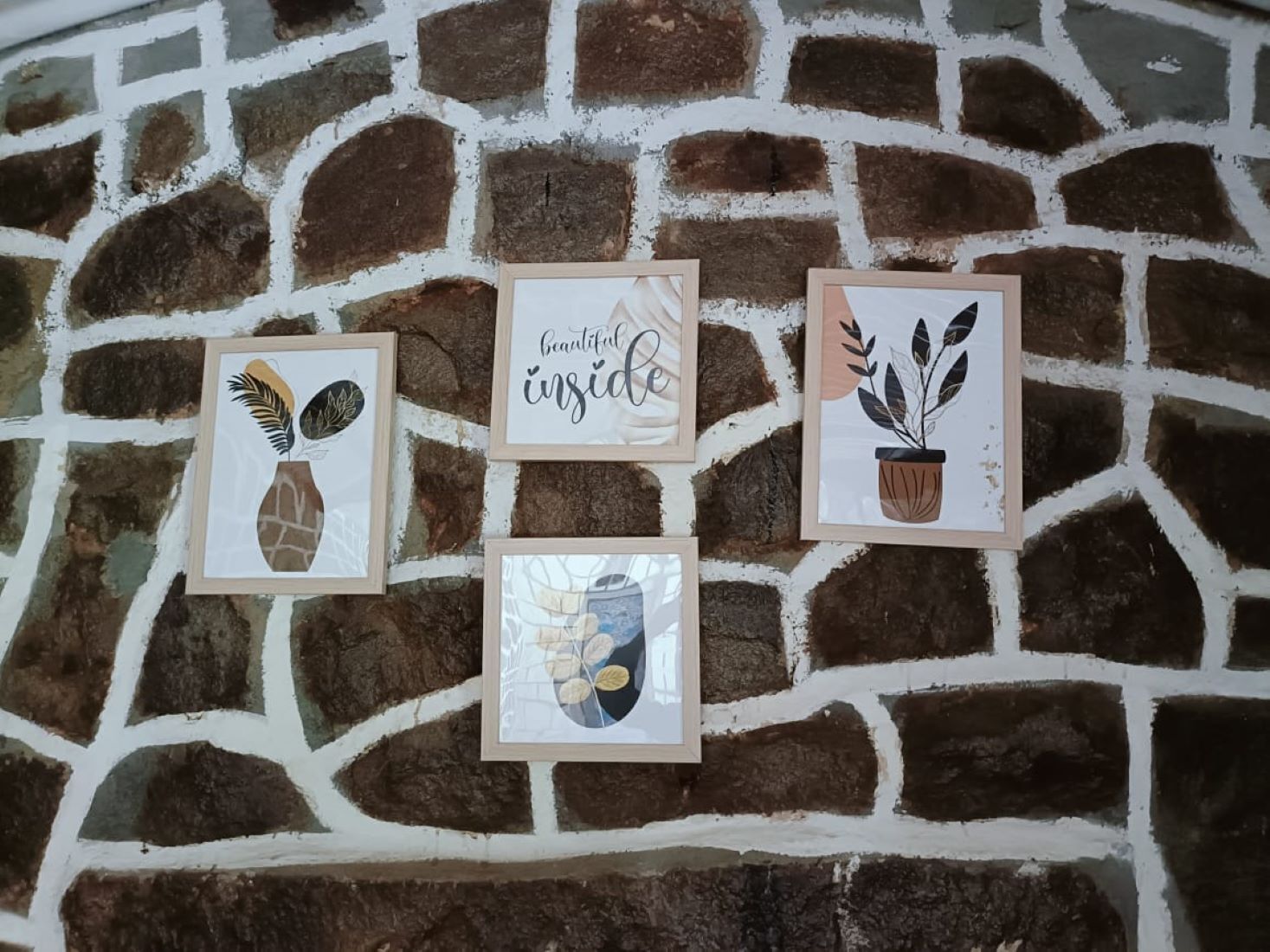 Four framed artworks on a stone wall.