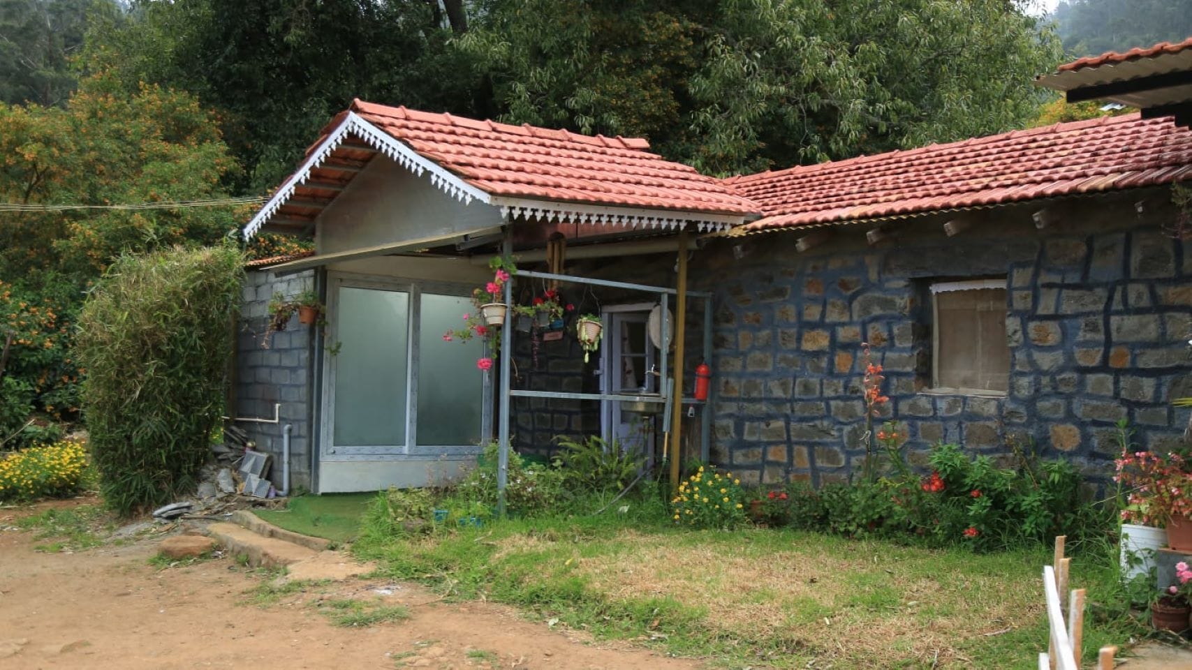 A stone house with a tiled roof, a covered porch, and a window.