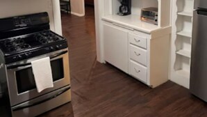 Une cuisine moderne avec des meubles blancs, une cuisinière en acier inoxydable et un four encastré.
