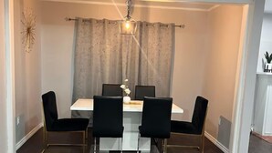 Un coin repas avec une table ronde, quatre chaises et un lustre.