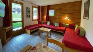 Una habitación acogedora con pared de madera, un sofá, una cama y una mesa.