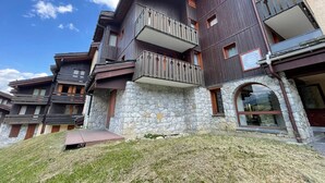 Un edificio de varios pisos con balcones, fachada de piedra y cielo despejado.