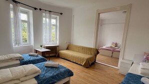 A room with two beds, a sofa, a small table, and a window with curtains. - Hideaway House 01 with Garden and FreeParking (Budapest)