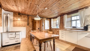 A wooden-paneled room with a wooden dining table, white cabinets, and a window with curtains. - Chalet Zimbablick in Bartholom Berg (Bartholomaeberg)
