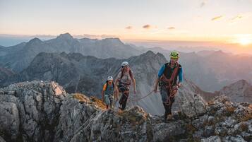 Un groupe d’alpinistes sur une crête montagneuse, avec un coucher de soleil en arrière-plan.