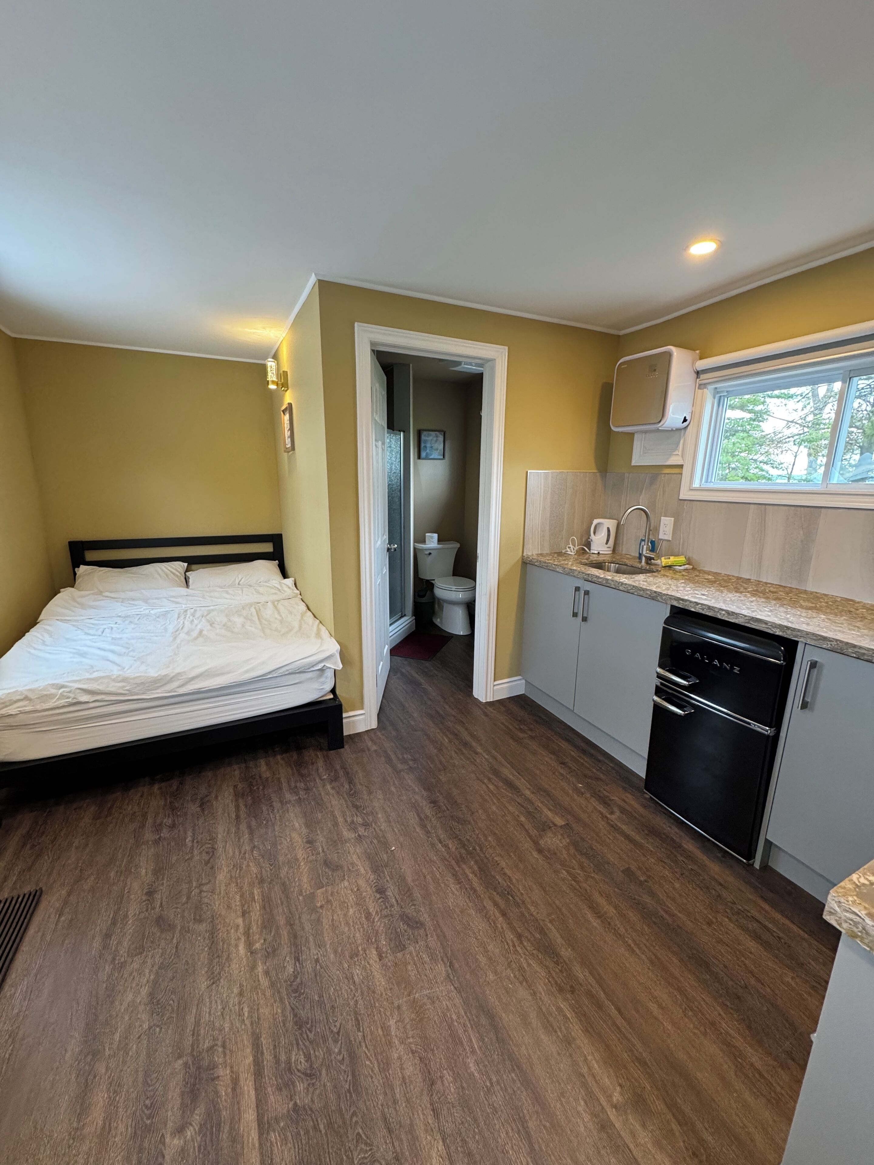 Une petite chambre comprenant un lit, une kitchenette et une salle de bain.