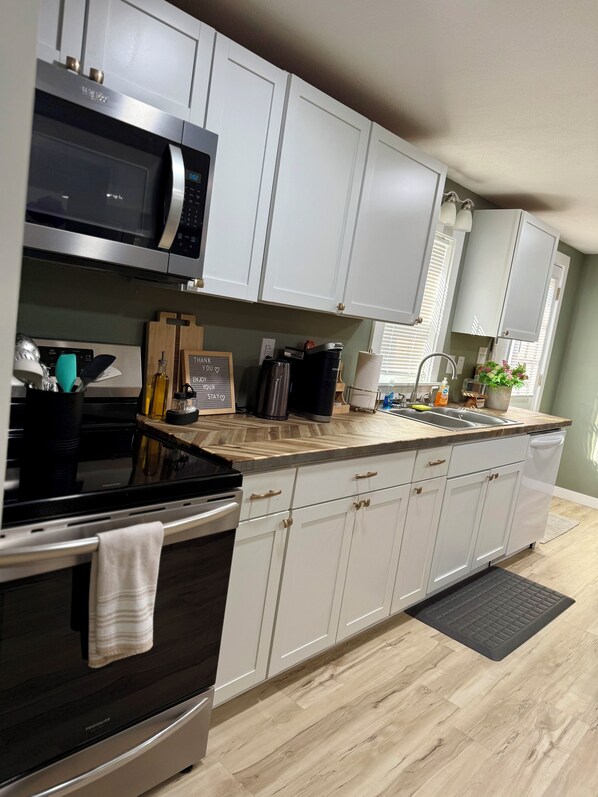 Una cocina moderna con armarios blancos, electrodomésticos de acero inoxidable y encimera de madera.