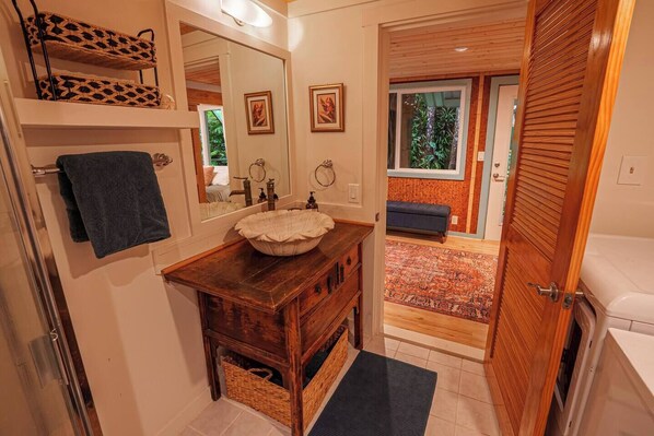 Un baño con tocador de madera, un espejo grande y vistas a un balcón con un tapete estampado.