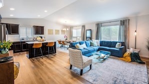 Una sala de estar moderna con un sofá azul, un sillón estampado y un comedor con una mesa y sillas.