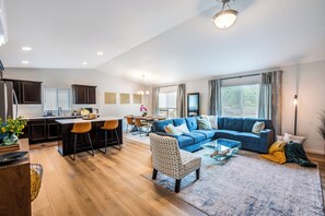 Enjoy a spacious living area with a sofa and armchair, a dining table, and a central kitchen island.