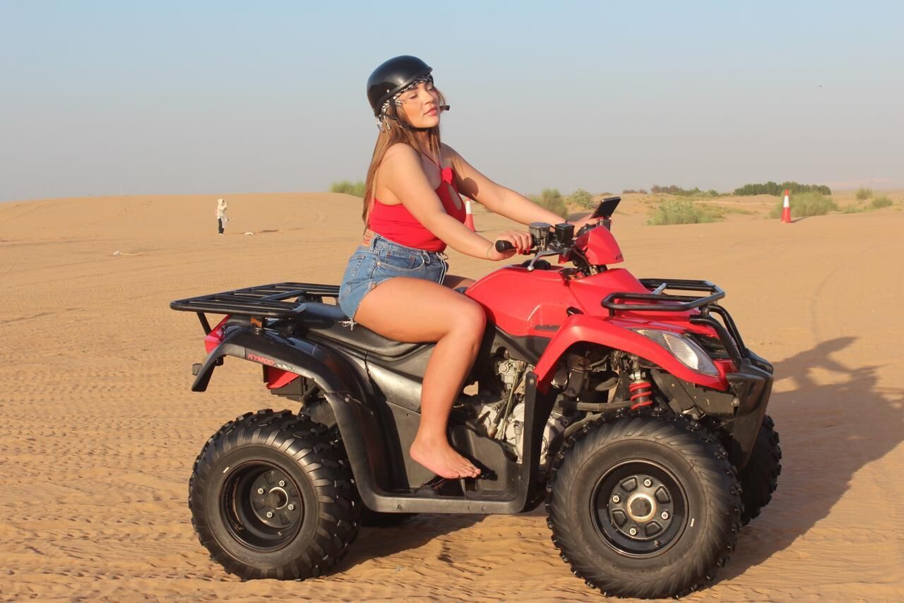 A person riding a red ATV in a desert.
