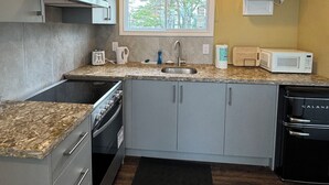 Une cuisine compacte avec des meubles gris, un four encastré, un four à micro-ondes et un évier.