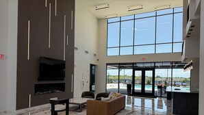 En rummelig lobby med stort TV, siddeområde og udsigt til en swimmingpool.