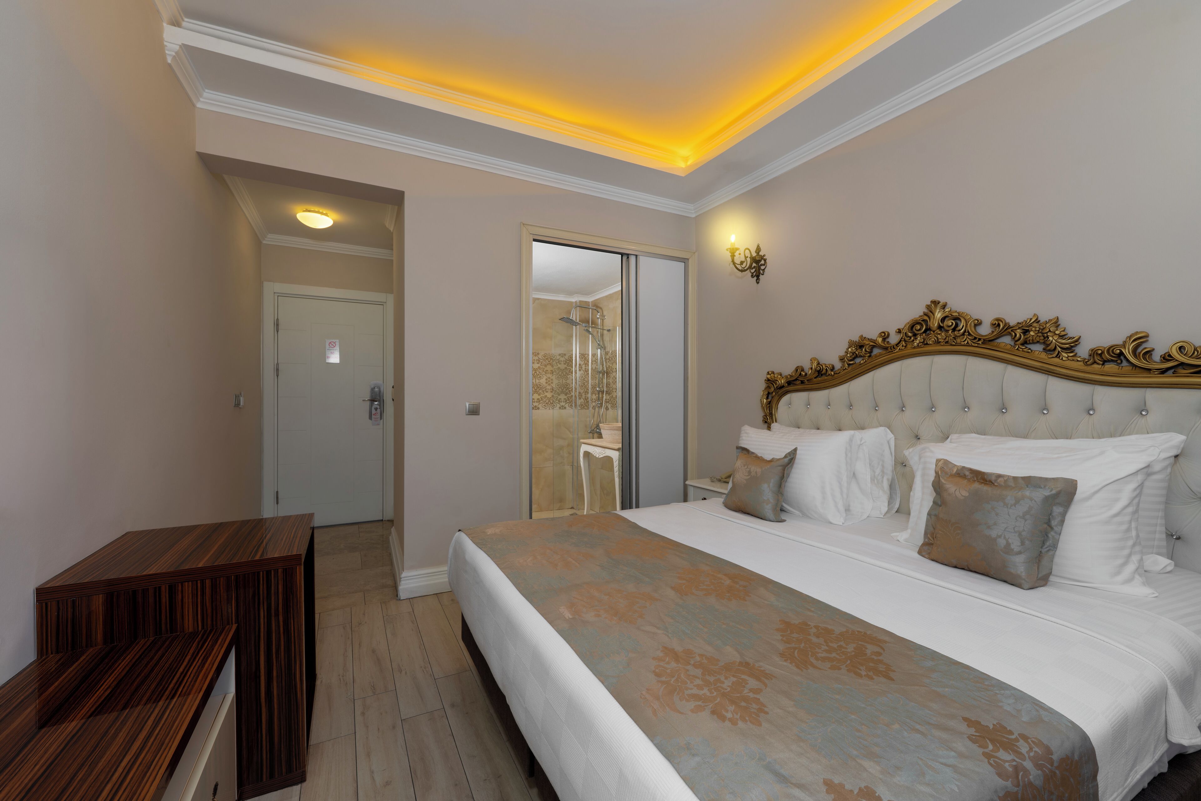 A bedroom with a large bed, a wooden bench, and a bathroom visible through an open door.