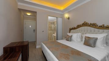 Un dormitorio con una cama grande, un banco de madera y un baño visible a través de una puerta abierta.