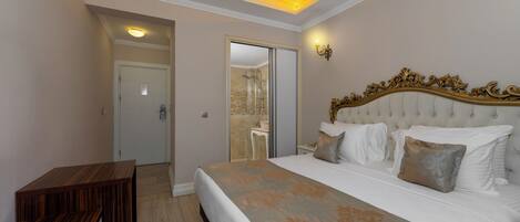 A bedroom with a large bed, a wooden bench, and a bathroom visible through an open door.