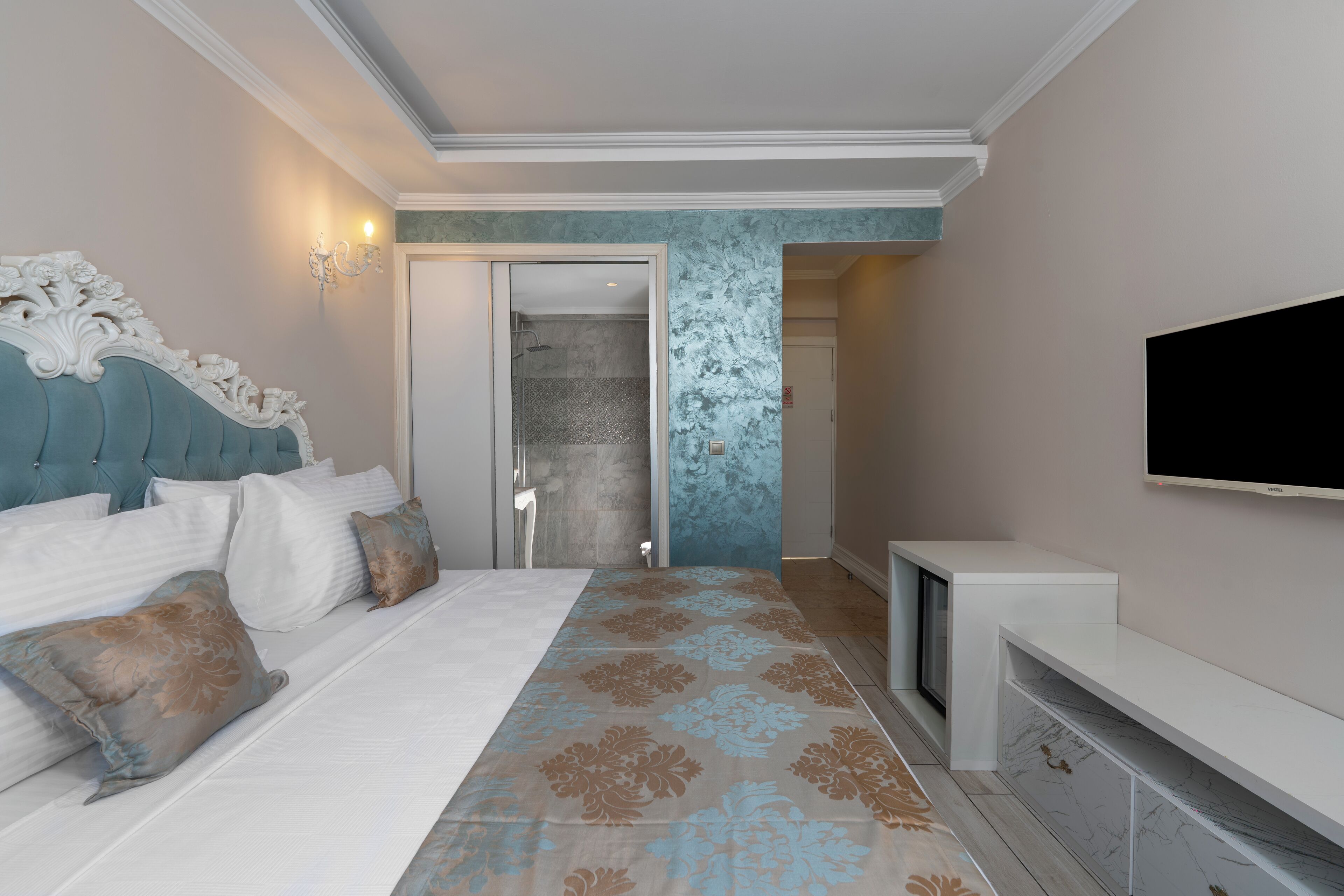 A modern hotel room with a large bed, a TV, and a bathroom visible through an open door.