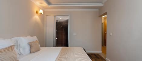 Habitación de hotel con una cama grande, un baño con ducha y un pasillo que conduce a otra habitación.