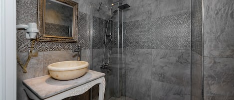 A bathroom with a marble sink, a mirror with an ornate frame, and a shower with a glass door.