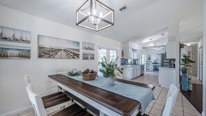 Une salle à manger spacieuse avec une longue table en bois, des chaises blanches et un lustre.